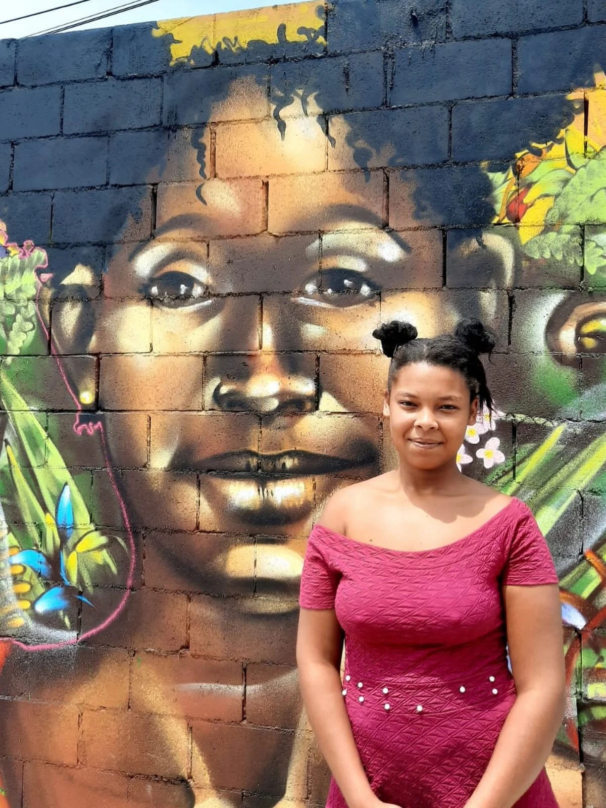 Mulher em pé diante de um grande retrato pintado em parede