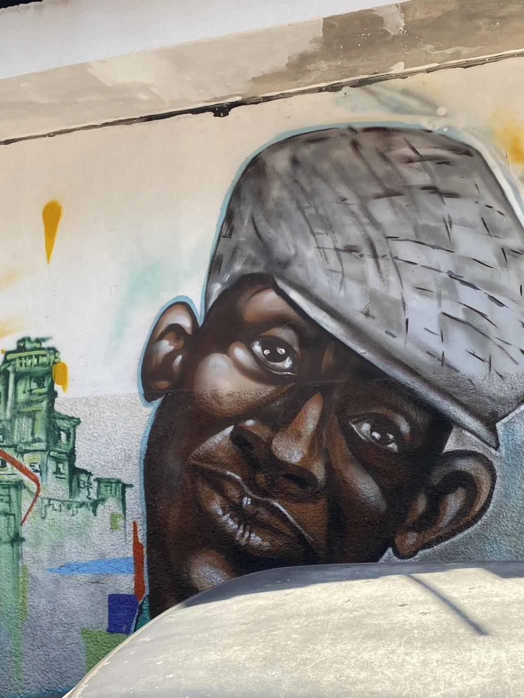 Detalhe de um retrato com boné pintado no muro
