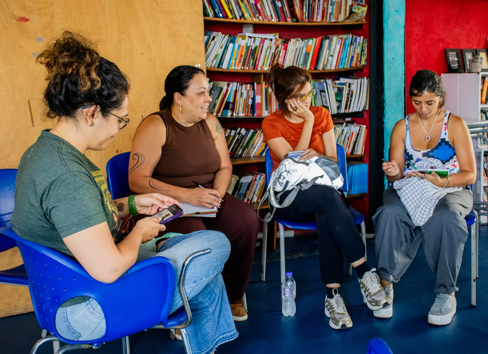 Visitantes sentadas conversam com cadernos e anotações nas mãos