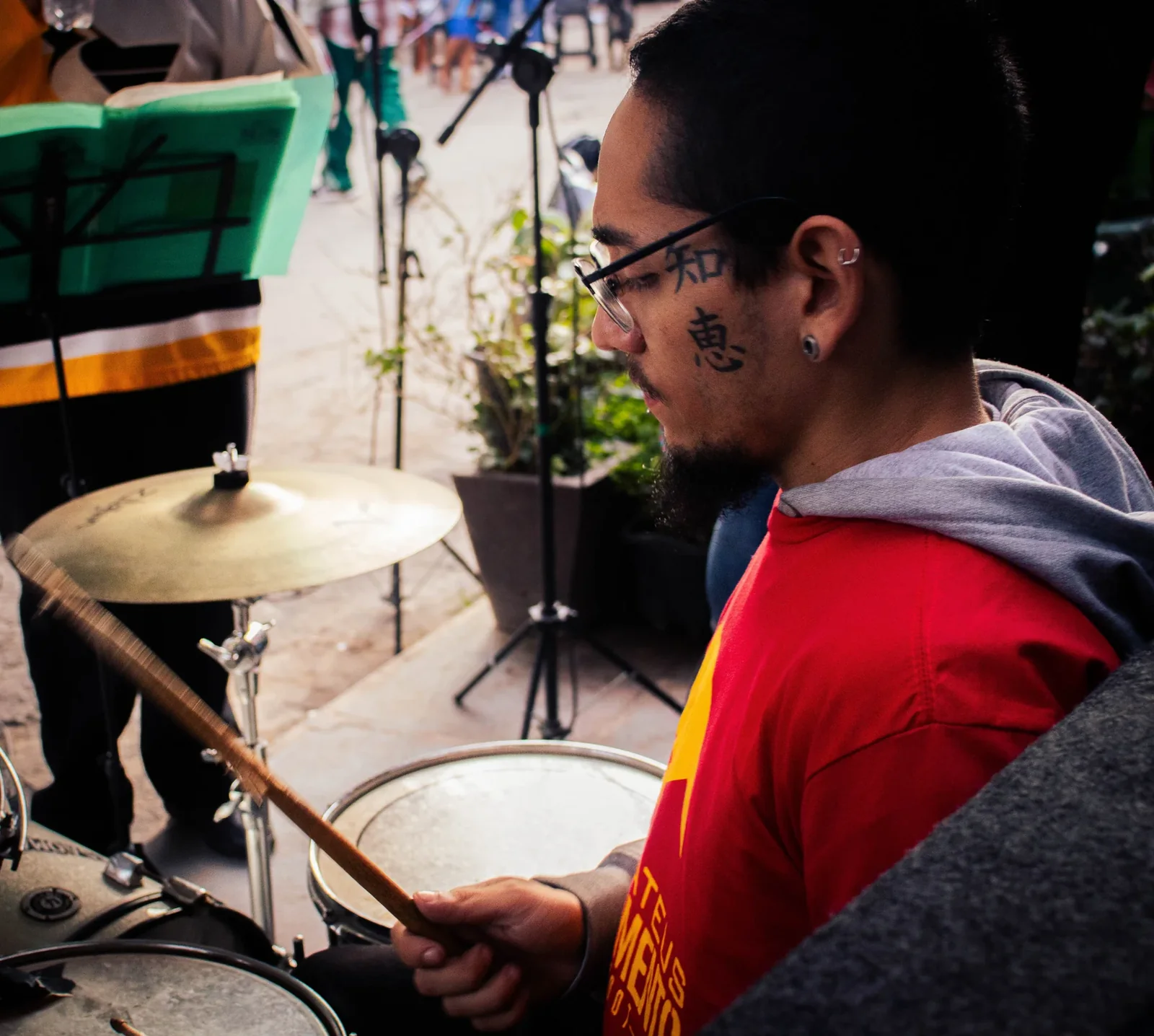 Músico de camiseta vermelha toca bateria em apresentação